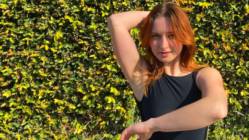 woman dancing in front of ivy-covered wall